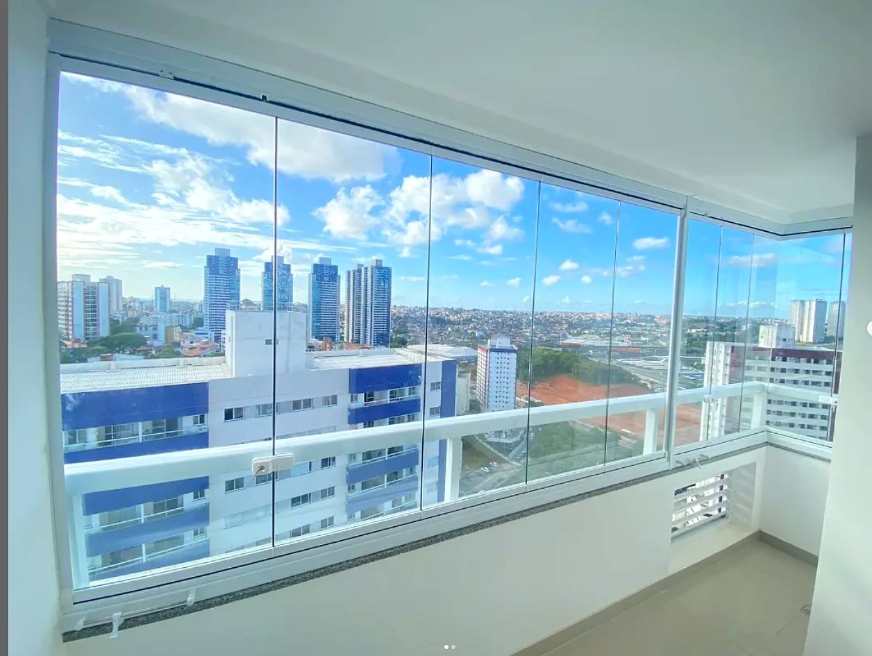 Sacada de apartamento com fechamento em vidro de canto, envidraçada do piso ao teto, com vista ampla da cidade