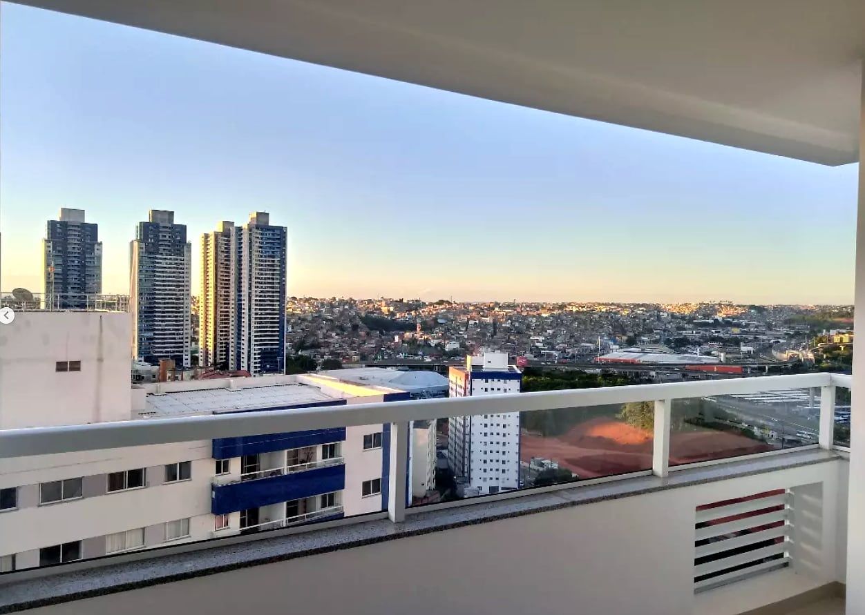 Sacada de apartamento com guarda-corpo de vidro e vista para a cidade ao entardecer